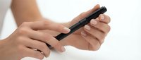 Woman checking blood sugar level with glucose meter device for diabetes management and health monitoring at home.