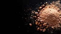 Aromatic roasted coffee beans scattered next to ground coffee powder on dark background, dramatic side lighting creates contrast for food photography and packaging.