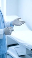 Medical professional wearing sterile gloves and blue surgical gown holding tablet device in clinical laboratory or hospital setting. Healthcare technology and patient care concept.
