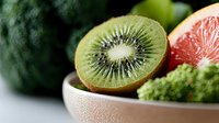Sliced kiwi fruit with grapefruit and broccoli in ceramic bowl, fresh produce for healthy eating and nutrition content.