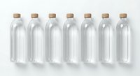 Seven clear glass bottles with natural cork stoppers arranged in row on white background for packaging design and branding projects.