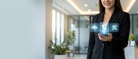 Professional Asian businesswoman using smartphone with digital technology icons in modern office environment for corporate communication and connectivity.