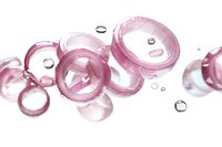 Translucent pink rings and water drops floating on white background, abstract macro photography with soft focus and light refraction effects for cosmetic designs.