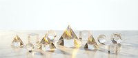Collection of transparent crystal diamonds and geometric gems scattered on white surface creating elegant luxury jewelry display for premium design projects.