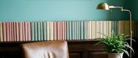 Modern home library interior with colorful book spines on wooden shelf, leather armchair and brass floor lamp creating cozy reading nook atmosphere.