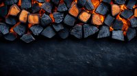 Burning charcoal and embers arranged in row on dark background, glowing orange fire beneath black coals creates dramatic contrast for grilling concept.