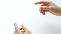 Gentle hands reaching toward each other in caring gesture on clean white background, symbolizing support, connection and human compassion in healthcare.