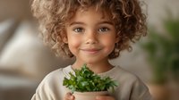 Mixed race child with curly hair smiling while holding potted fresh herbs, wearing beige sweater. Natural window light creates warm atmosphere for lifestyle and parenting content.