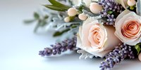 Delicate peach roses paired with purple lavender sprigs and dusty miller leaves create romantic floral arrangement on soft blue background. Perfect for wedding design.