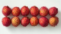 Fresh ripe red rambutan fruits arranged in neat rows on white background, exotic tropical fruit composition showing detailed spiky skin and vibrant color.