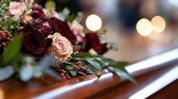 Elegant floral arrangement with deep burgundy and blush pink roses resting on polished wooden surface against soft bokeh lights, creating romantic wedding atmosphere.