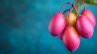 Fresh ripe mangoes hanging from branch with green leaves against vibrant blue background, tropical fruit harvest concept for healthy eating and nutrition.