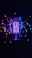 Vintage Edison bulb with electric lightning bolts and colorful bokeh lights on dark background for creative energy and innovation concepts.
