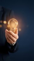 Businessman hand holding glowing light bulb representing innovation, creativity and bright ideas for business success and entrepreneurship solutions.