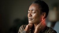 African American woman experiencing neck pain and discomfort, touching sore throat area with concerned expression in indoor setting for health awareness.