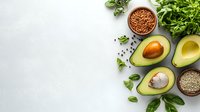 Fresh halved avocado with herbs, seeds and spices on light concrete background. Raw ingredients for healthy cooking with copy space for text.