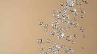 Sparkling clear diamonds and gemstones scattered on warm beige background for luxury jewelry design and precious stone collection displays.
