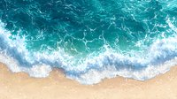 Aerial view of turquoise ocean waves gently washing onto a sandy beach, with white sea foam creating a stunning coastal scene.