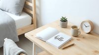 Minimalist wooden desk with open notebook, small succulent plant, ceramic mug, and analog clock in a cozy Scandinavian bedroom interior.