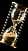 Golden sand hourglass with brass frame isolated on black background, symbolizing time passage, deadline, and urgency for business and conceptual projects.