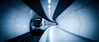 Modern subway train speeding through illuminated underground tunnel with tiled walls and motion blur effect creating dynamic urban transportation scene.