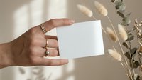 Hand holding blank white card mockup with dried pampas grass and eucalyptus branches in soft natural light for branding and stationery design projects.