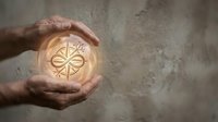 Protective hands cupping glowing compass symbol representing guidance, direction and navigation in business planning and life decisions.