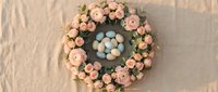 Easter wreath with pink roses and blue eggs on textured background for spring holiday decoration and seasonal greeting cards.