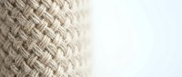 Natural woven rope texture with detailed braided pattern on white background. Close-up macro photography showing fiber craftsmanship for nautical and rustic designs.
