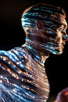 Silhouette of person illuminated by glowing blue and white light streaks against dark background, creating futuristic technological effect for creative design.