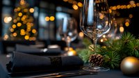 Empty wine glass on elegant table setting with black napkin, pine branches, ornaments and bokeh lights creating festive holiday atmosphere. Perfect for restaurant menu.
