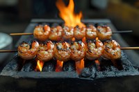 Grilled jumbo shrimp skewers cooking over hot charcoal with bright flames. Close-up view shows perfectly seasoned seafood with charred marks and juicy texture.