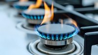 Blue flames burning on modern gas stove burner in kitchen, close-up view showing cooking equipment in operation.
