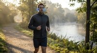 Athletic African American man jogging along scenic river path during golden hour sunrise workout session for healthy lifestyle and fitness motivation.