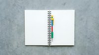 Open spiral notebook with colorful page dividers and blank pages on concrete surface for office organization and note-taking projects.