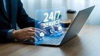 Professional businessman using laptop with glowing 24/7 service holographic interface displaying customer support icons for continuous assistance.