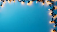 Glowing Christmas lights creating corner border frame on turquoise blue background with copy space for seasonal holiday greeting cards and festive designs.