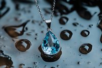 Elegant teardrop pendant necklace with blue topaz gemstone on silver chain against water droplets background, showcasing luxury jewelry detail and craftsmanship.