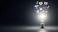 Glowing light bulb with floating medical icons including stethoscope, heart, cross and pills representing healthcare innovation and bright ideas.