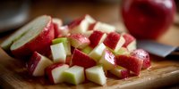 Fresh diced red radishes on wooden cutting board ready for cooking and salad preparation in modern kitchen setting.