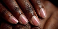 Professional manicure with nude pink nail polish on dark skin hands showcasing elegant fingernails and beauty care routine for salon services.