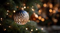 Elegant blue and gold Christmas ornament hanging on evergreen tree branch with warm bokeh lights creating festive holiday atmosphere for seasonal decorations.