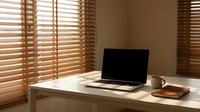 Modern home office workspace with laptop computer on white desk near wooden blinds creating warm natural lighting for remote work productivity.