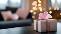 White gift box with pink bow and glitter ribbon on wooden table against blurred Christmas lights background creating magical festive atmosphere.