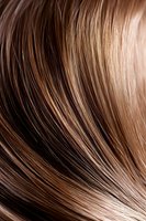 Close-up macro shot of shiny brown hair strands showing smooth texture and natural highlights, suitable for beauty and haircare advertising materials.