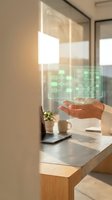Hand presenting holographic digital interface with green glowing elements in modern office workspace for technology and innovation concepts.