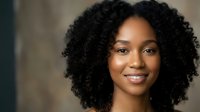 Professional African American woman with natural curly hair smiling confidently at camera. Corporate headshot for business, career and workplace diversity.