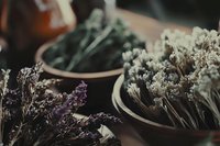 Dried flowers and herbs in rustic ceramic bowls create moody vintage atmosphere with purple lavender and white baby's breath in dark tones for natural decor.