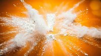 Explosive orange burst with white powder splash creating dynamic radial motion. High-energy abstract background for advertising, sports, and creative projects.