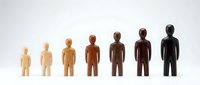 Wooden figurines in increasing sizes and darkening skin tones arranged in a row, representing diversity, growth, and progression for educational, business, and social concepts.